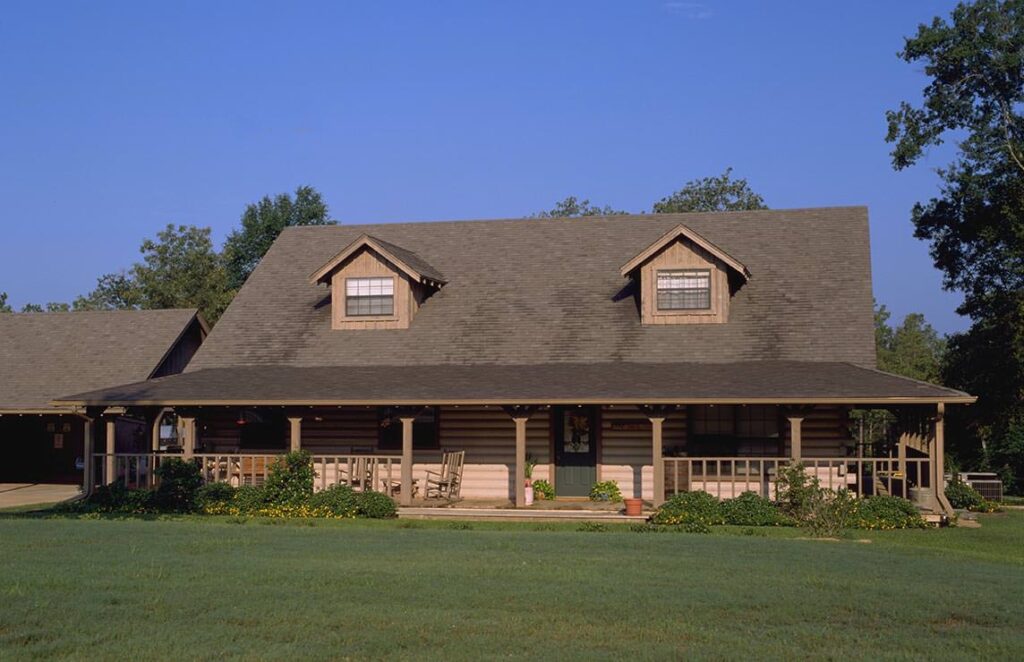 The picture showcases a beautifully built log home with a stunning tan-colored roof.