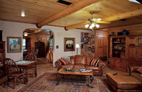The image showcases a warm, inviting log home's living room, equipped with comfortable leather furniture and a cozy fireplace for relaxation and leisure.