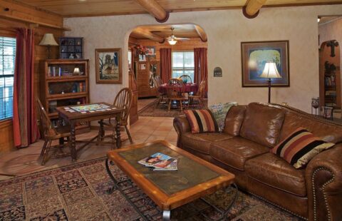 The image showcases a cozy living room in one of our log homes, featuring a luxurious brown leather couch.