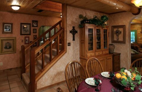 The image showcases a rustic dining room set within a beautifully crafted log cabin, exuding warmth and character.