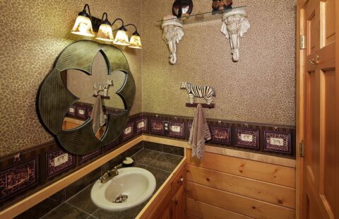The image depicts a stylishly designed bathroom in one of our log homes, featuring a sleek sink and mirror.