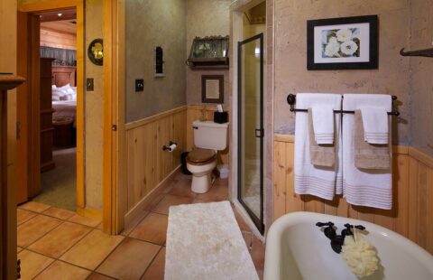 The image showcases a cozy, rustic bathroom fitted with beautiful wood paneling and a modern toilet, reflecting our company's unique blend of natural textures and contemporary comfort in log home construction.
