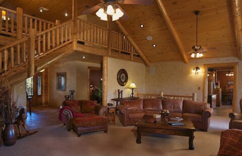 The image displays a cozy and inviting living room inside one of our beautifully crafted log homes, featuring natural wood design elements.