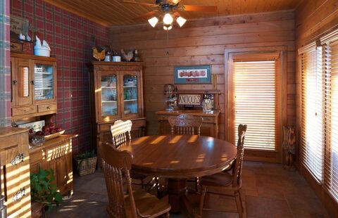 The image showcases a cozy, rustic dining room beautifully crafted within our log cabin featuring solid wooden furniture and warm, ambient lighting.