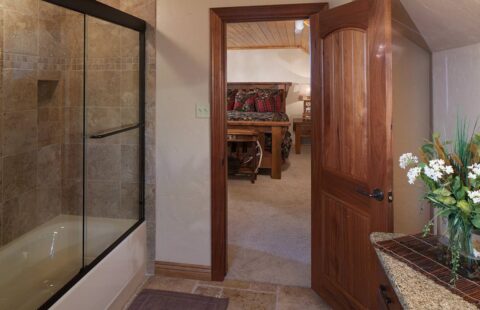 The image showcases a rustic-style bathroom in one of our log homes, featuring a well-designed shower and sink.