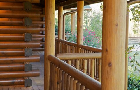 The image showcases a beautifully-crafted wooden railing adorning the porch of our log home.